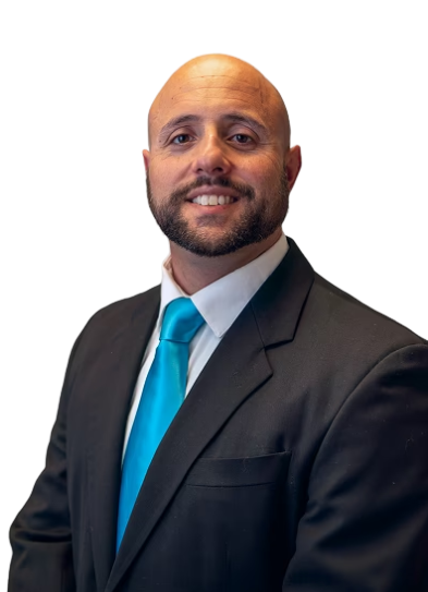Smiling bald man with beard wearing a black suit, white shirt, and turquoise tie.