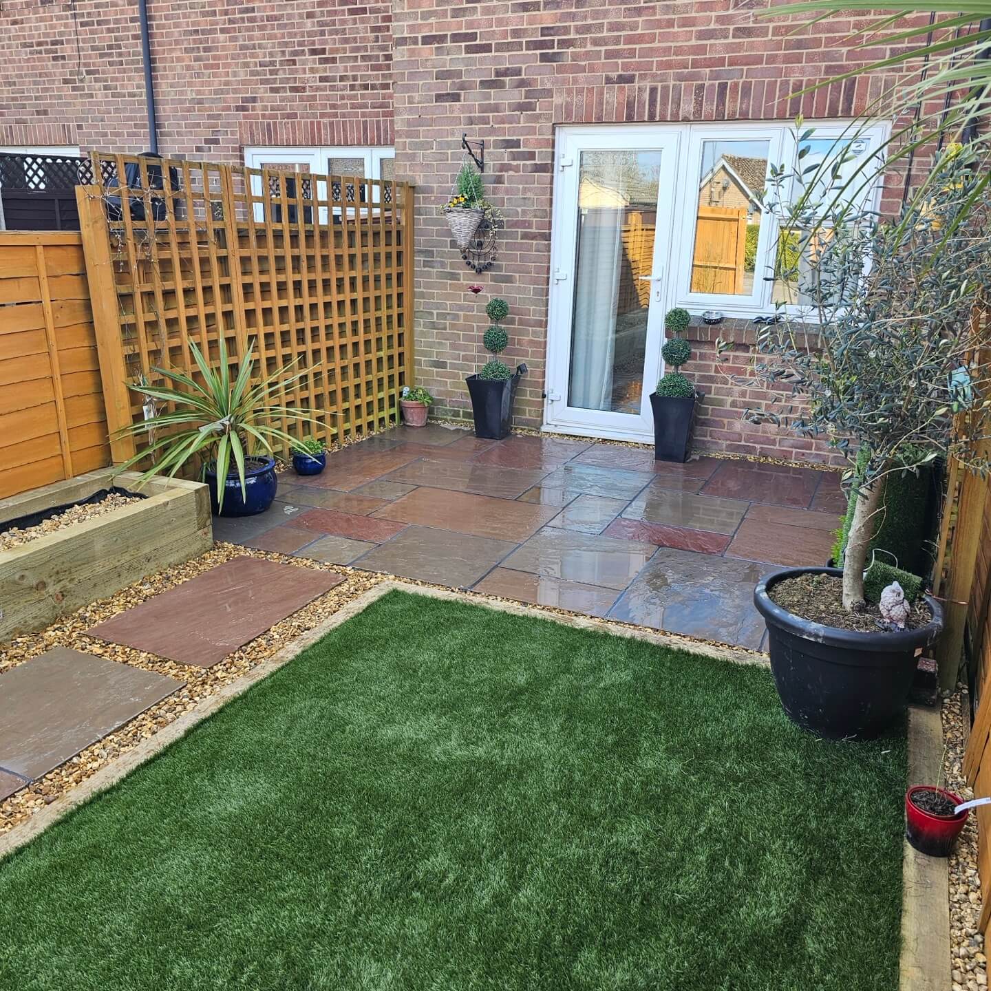 a patio with a green lawn and plants