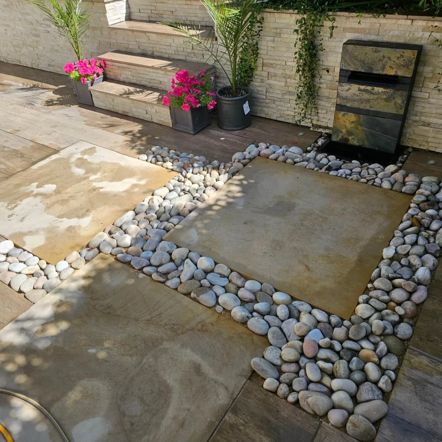 a stone patio with a brick wall and plants