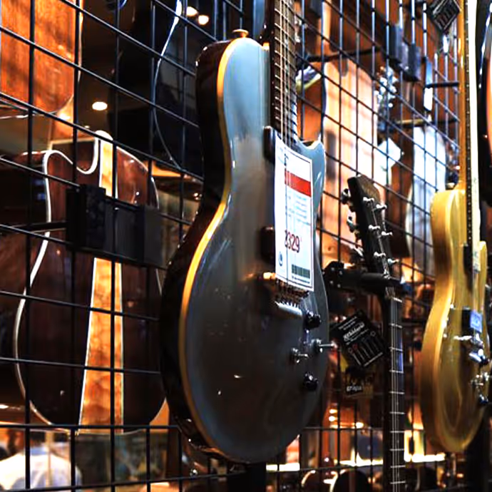 Electric guitars hanging on display in a music store, with one gray guitar prominently featured in the center.