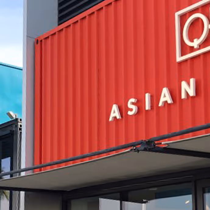 Red container-style building facade with the word 'ASIAN' in white capital letters, part of a restaurant or food venue sign.