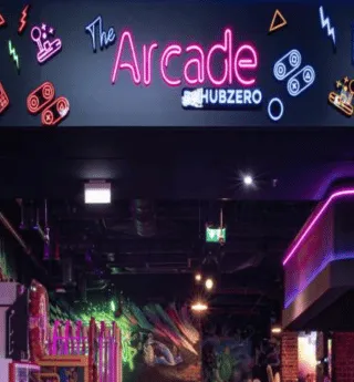 Neon sign reading 'The Arcade Hub Zero' at the entrance of a gaming arcade with colorful lights and decorations.
