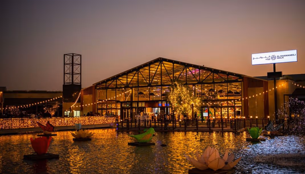 Modern waterfront building illuminated at dusk with lights reflecting on the water.