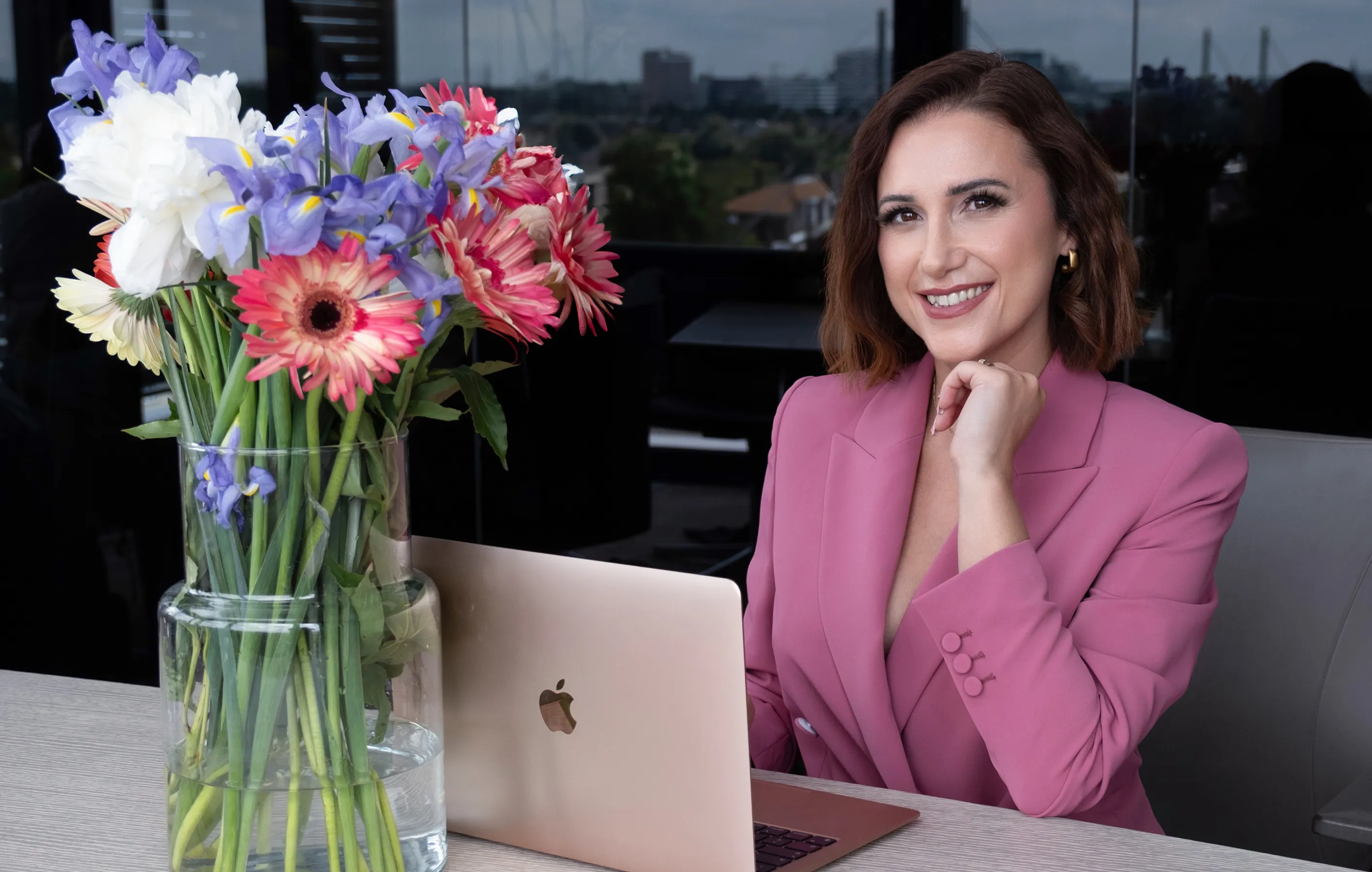 Emilia Bolda mit Macbook am Tisch sitzend auf dem Blumen stehen