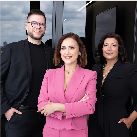 Das Team von Investiere Dich Frei, Arm in Arm stehend in schicker Kleidung