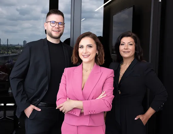 Das Team von Investiere Dich Frei, Arm in Arm stehend in schicker Kleidung