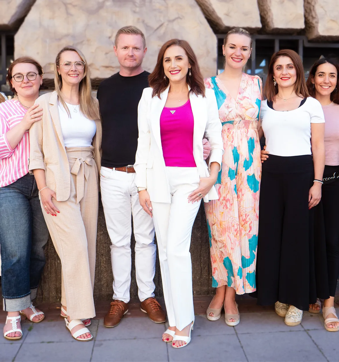 Das Team von Investiere Dich Frei, Arm in Arm stehend in schicker Kleidung