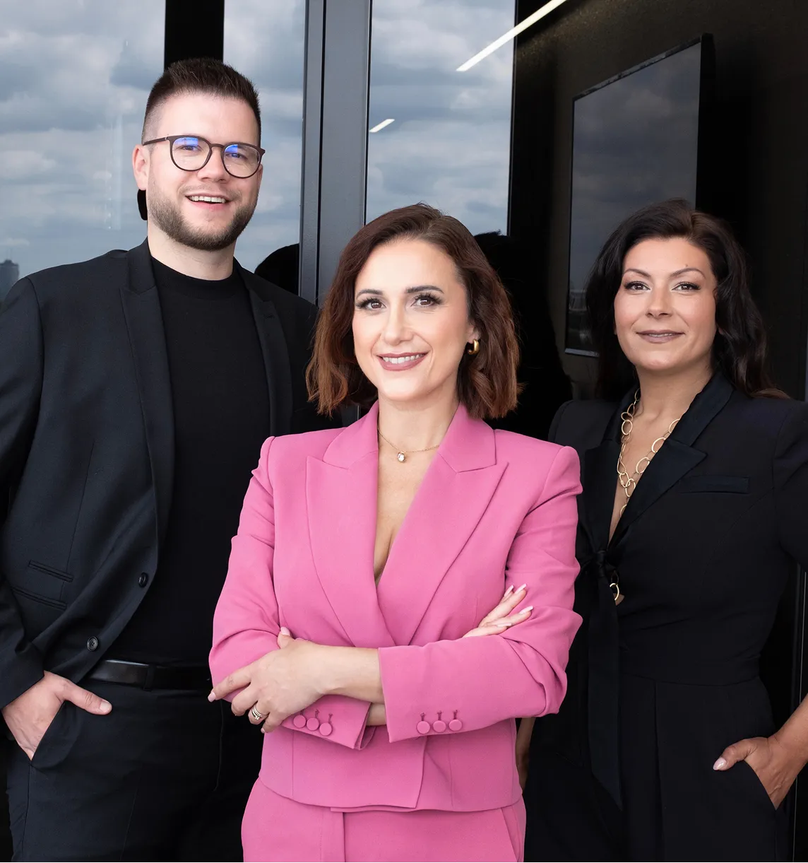 Das Team von Investiere Dich Frei, Arm in Arm stehend in schicker Kleidung