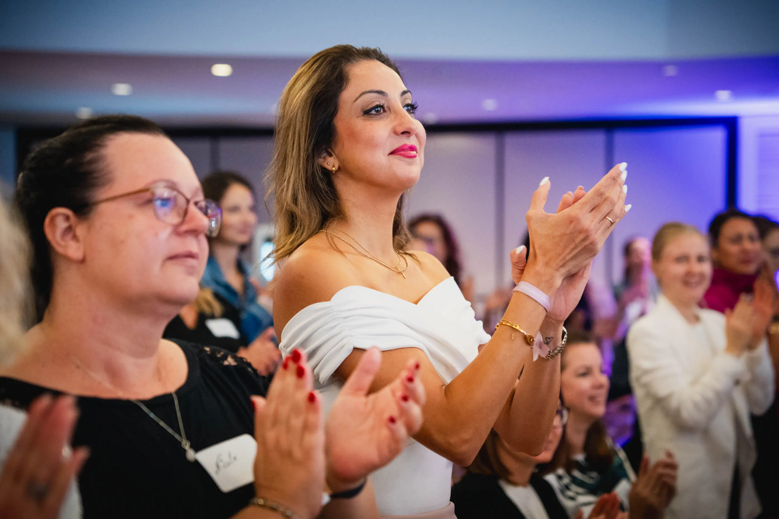 Eine Gruppe junger Frauen, die beim Investiere Dich Frei Summit im Publikum stehen und applaudieren