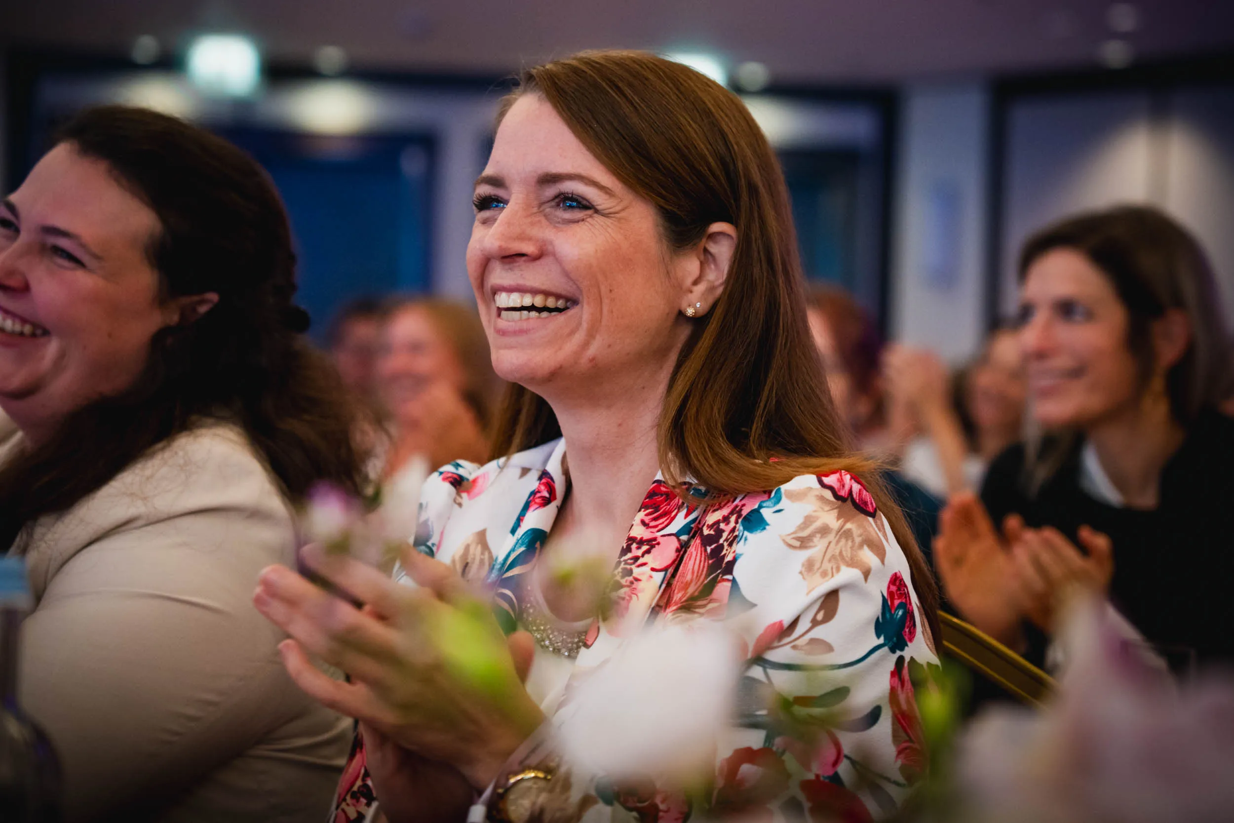 Eine Gruppe junger Frauen, die beim Investiere Dich Frei Summit im Publikum stehen und applaudieren