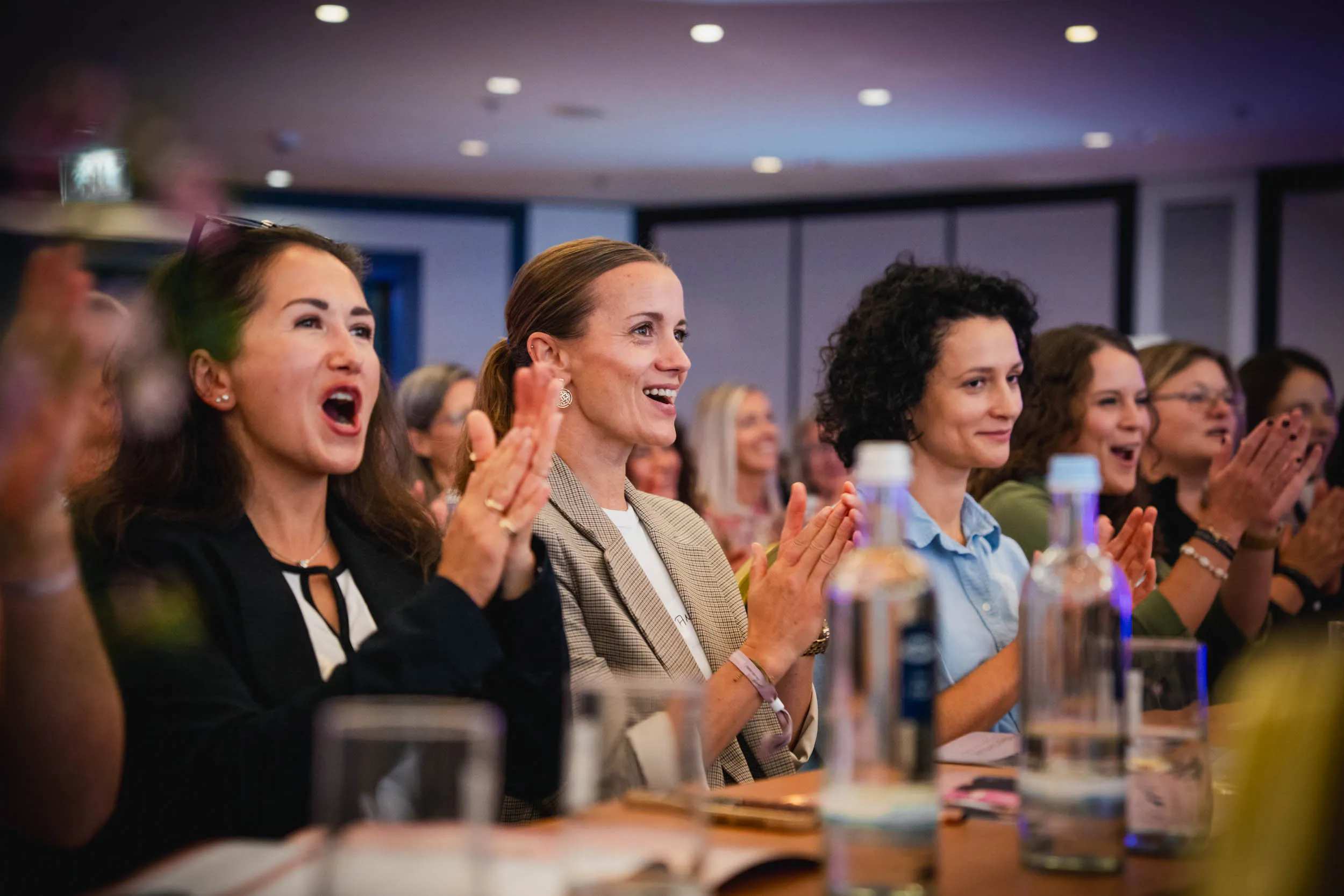 Eine Gruppe junger Frauen, die beim Investiere Dich Frei Summit im Publikum stehen und applaudieren
