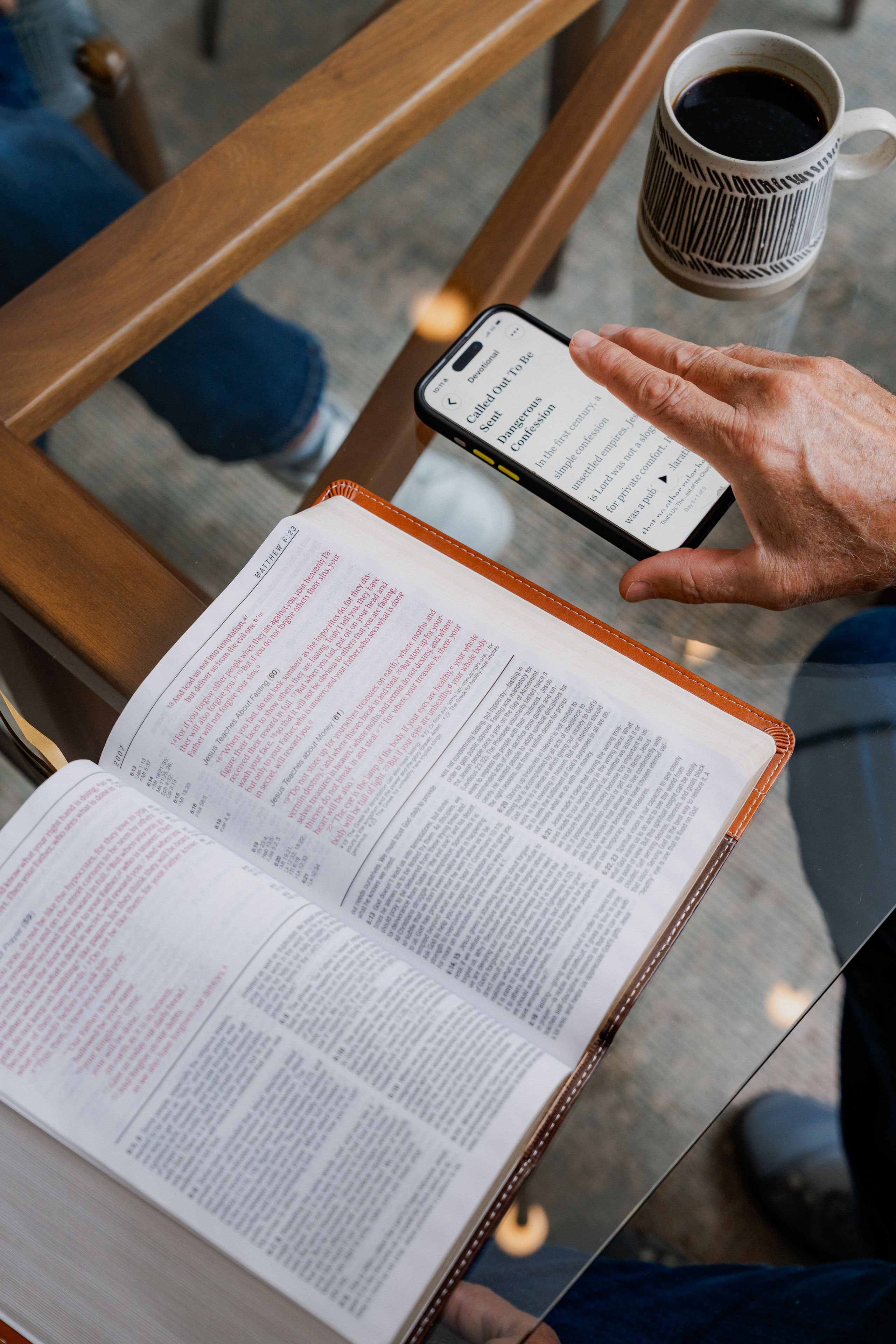 An open Bible beside a phone displaying the YouVersion Bible App