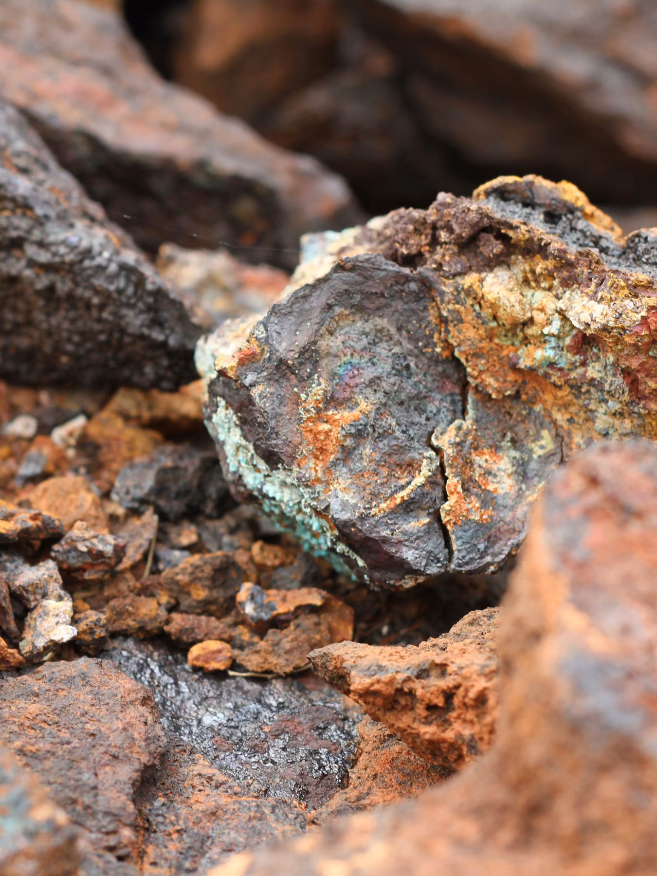 Close-up of rough copper ore rocks with brown, orange, and green mineral deposits.