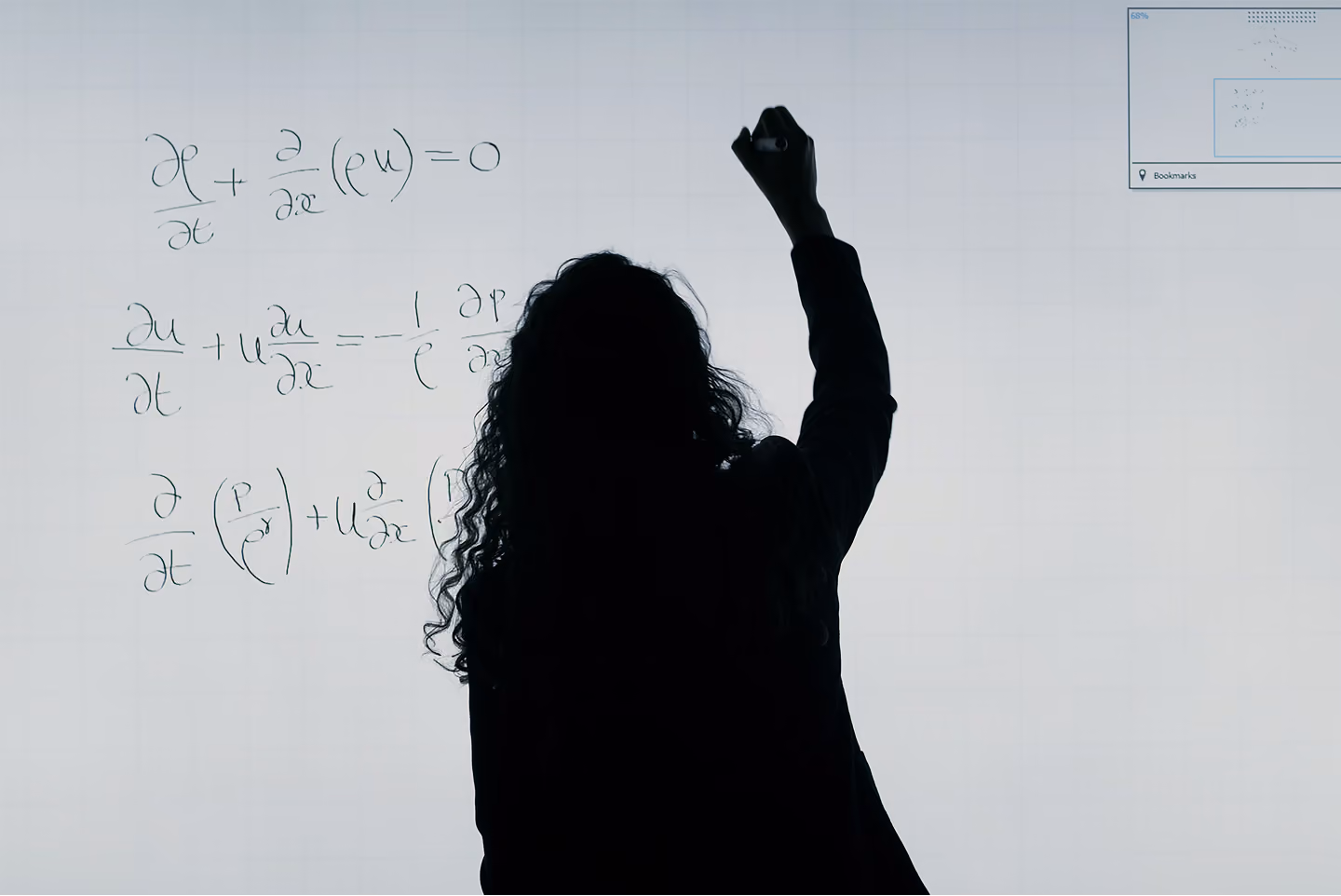 Silhouette of a womans back writing some equations on a lightbox