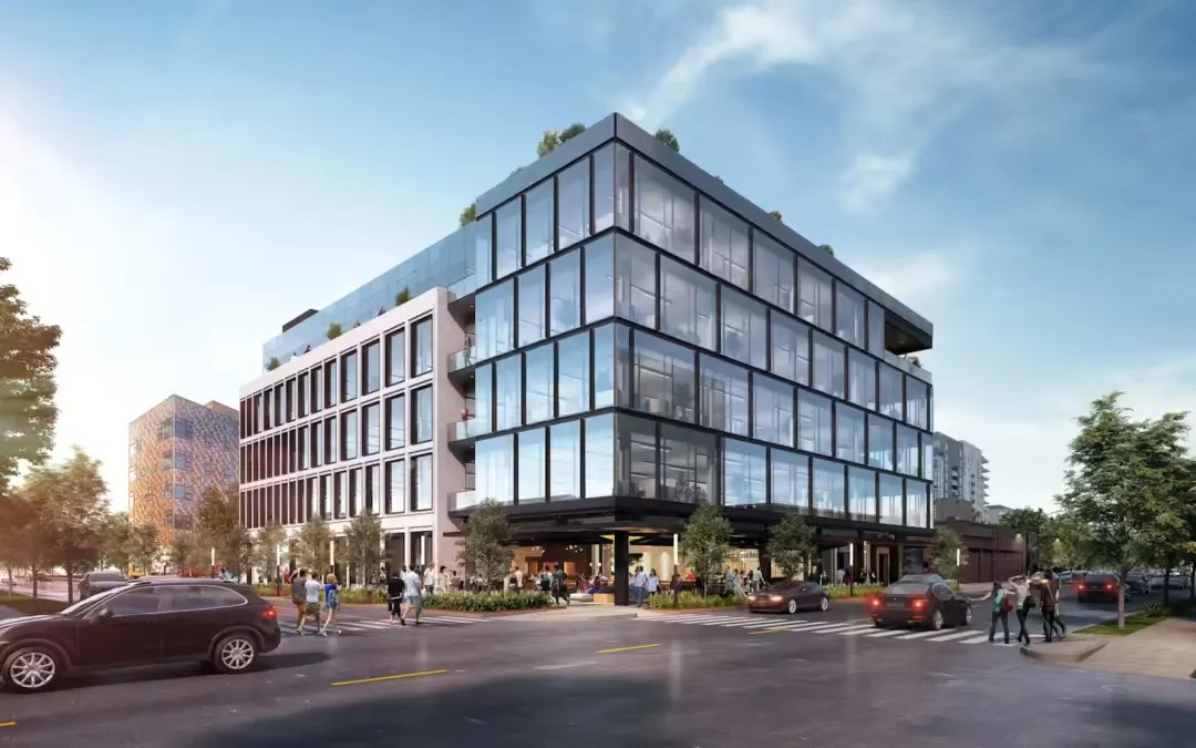 Modern multi-story office building with glass facade on a busy urban street with cars and pedestrians.