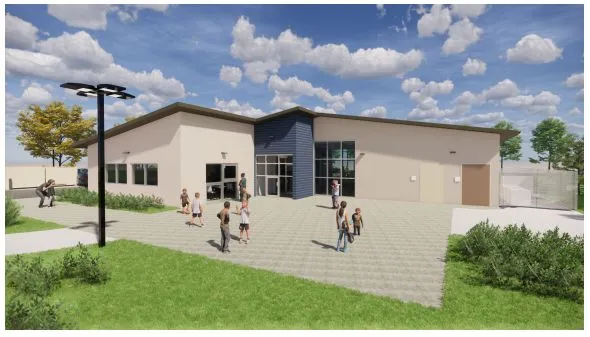 Modern single-story building with people walking outside on a paved area under a blue sky with clouds.
