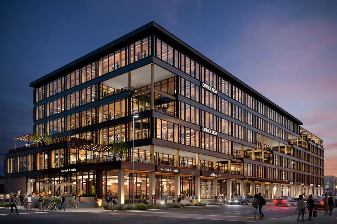 Modern multi-story commercial building at dusk with large glass windows, lit office spaces, retail shops, and people walking outside.