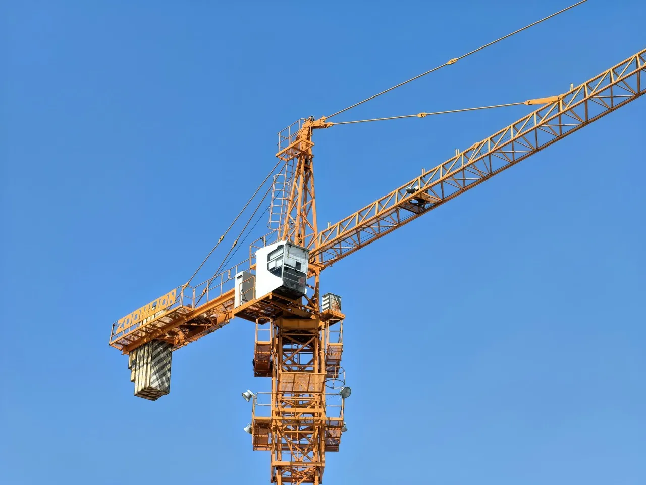 Orange construction tower crane against a clear blue sky.