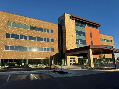 Modern four-story commercial building with brick and glass facade under clear blue sky.