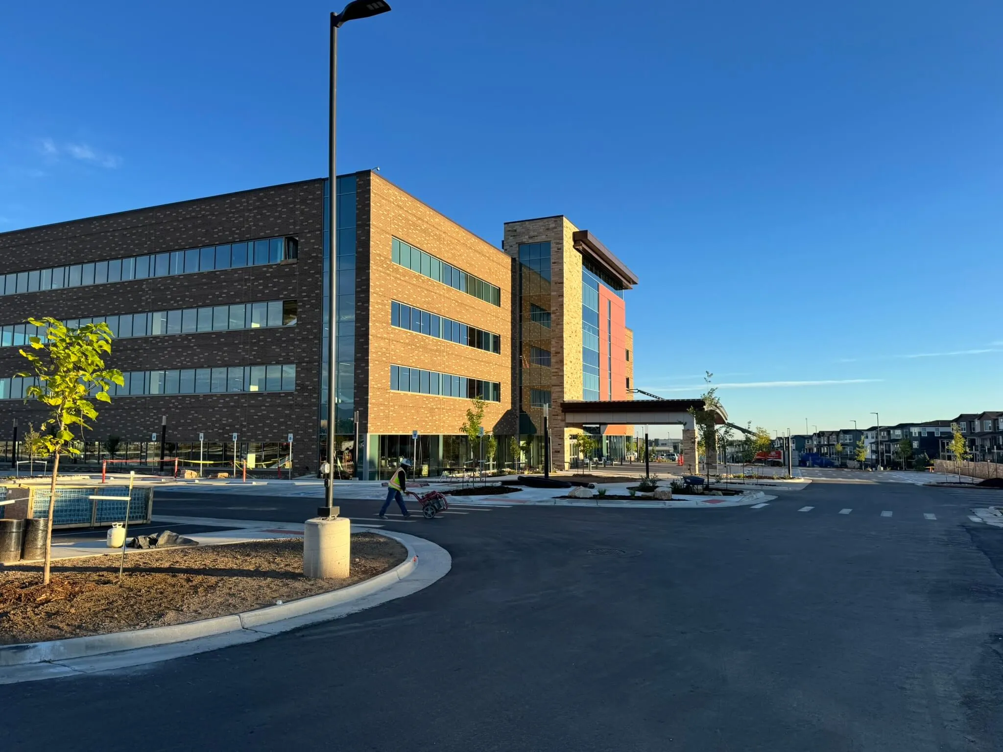 Modern four-story office building with large windows and brick facade under clear blue sky.
