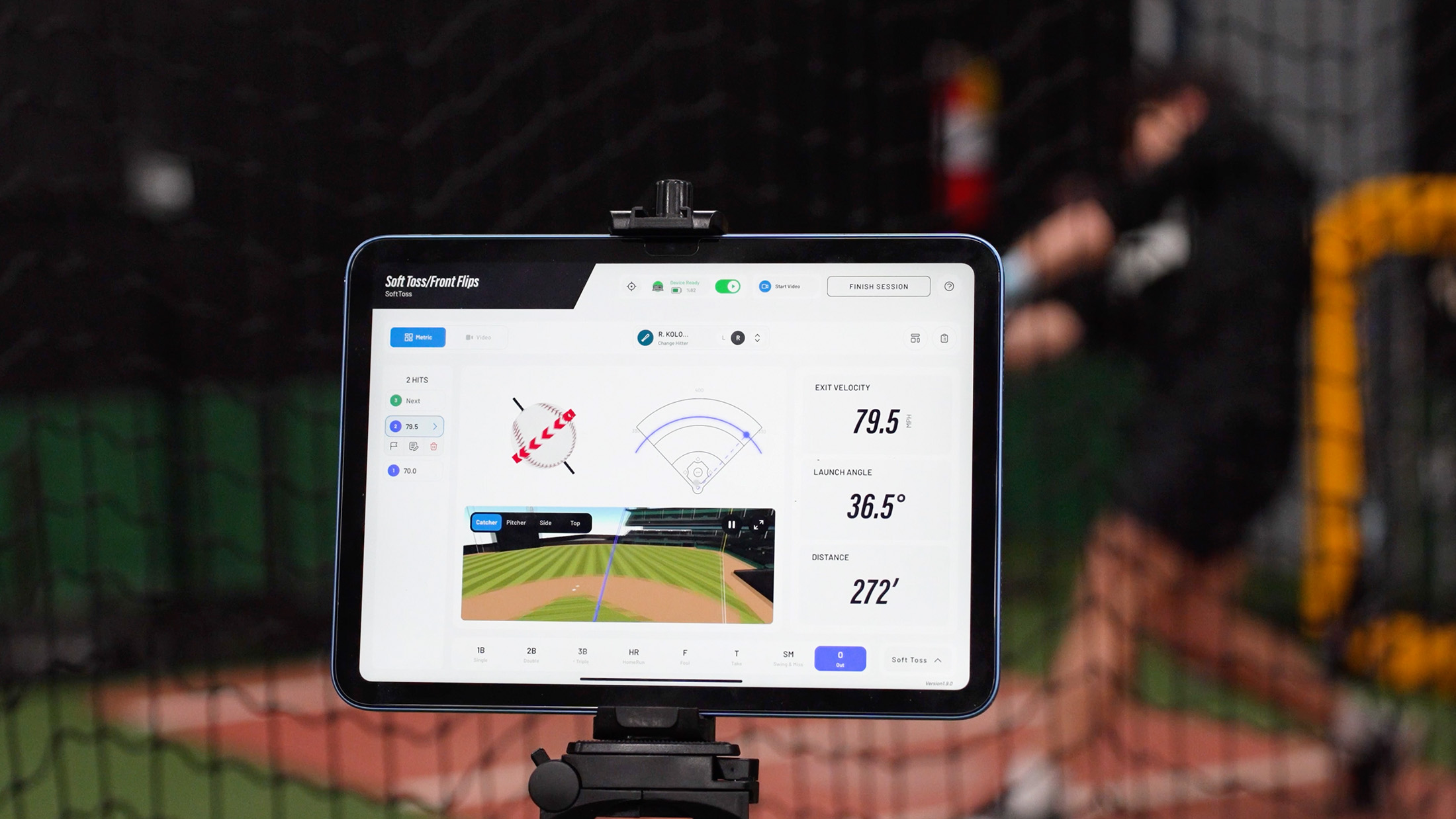 People walking on a paved path on a sunny day near a baseball area, some carrying baseball bags and equipment.