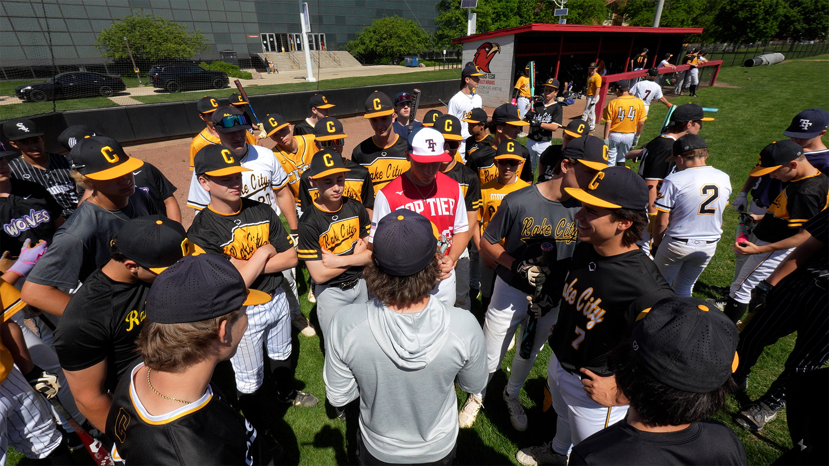 Coach leading a team huddle with travel baseball players on the field