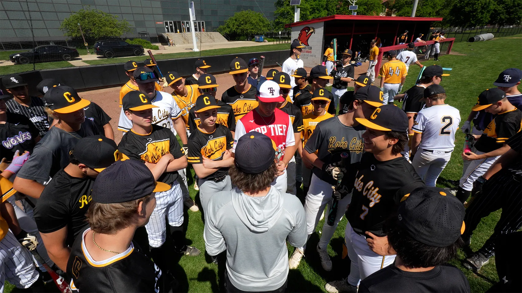 Coach leading a team huddle with travel baseball players on the field