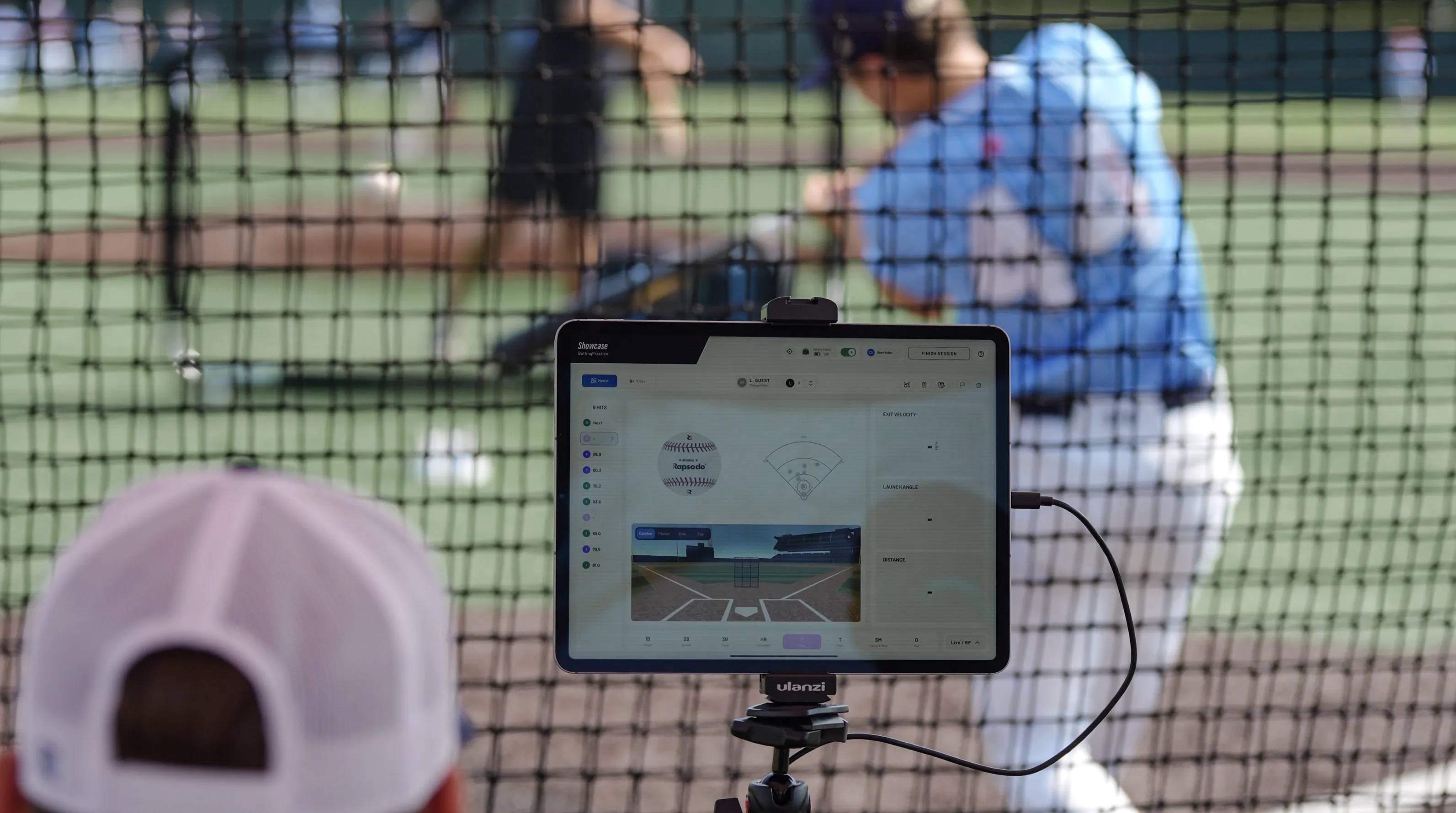 Hitter swinging in the cage while a tablet on a tripod captures his swing data