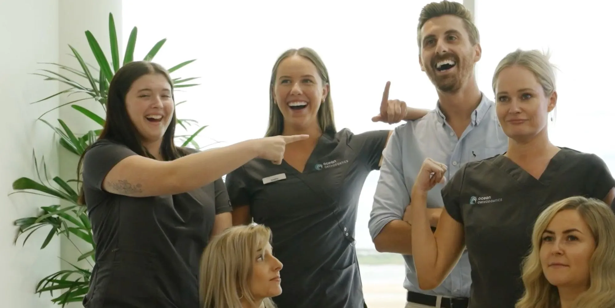 The team at Ocean Orthodontics standing next to each other and laughing.