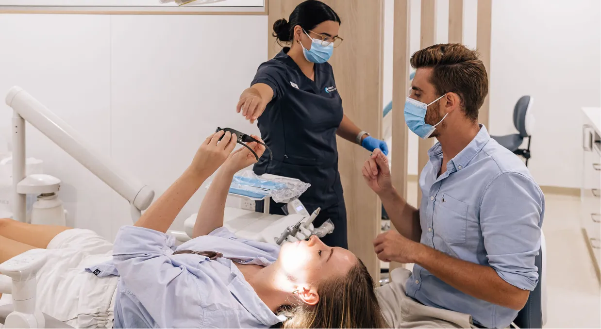 A woman laying in a dentist's chair in a dentist's surgery.