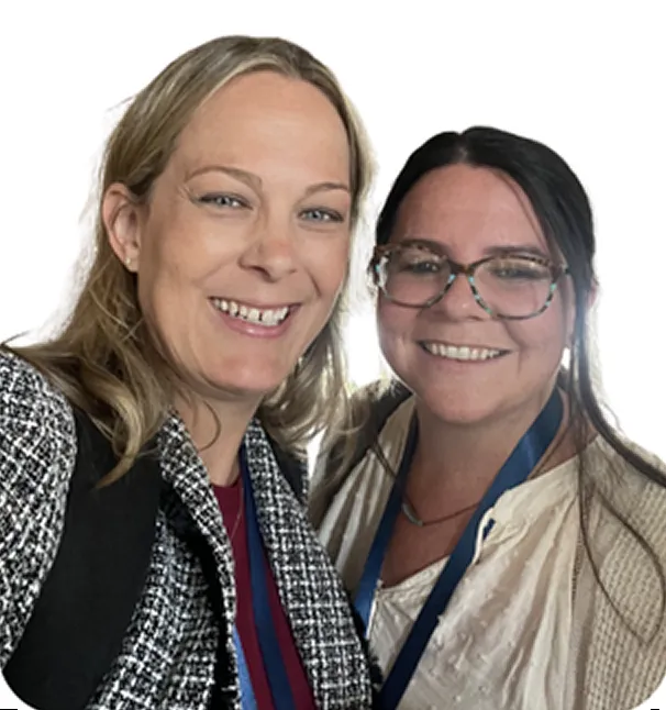 Two smiling women posing closely for a selfie, one with blonde hair wearing a patterned jacket and the other with dark hair, glasses, and a light blouse.