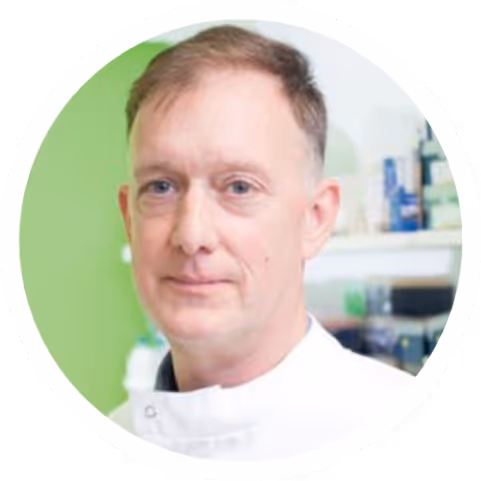 Portrait of a middle-aged man in a white lab coat with a blurred laboratory background.