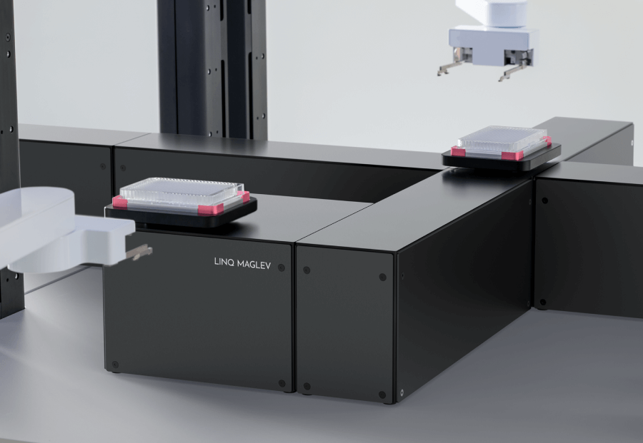 Black LINQ MAGLEV device with robotic arms handling lab sample trays in a clean laboratory setting.