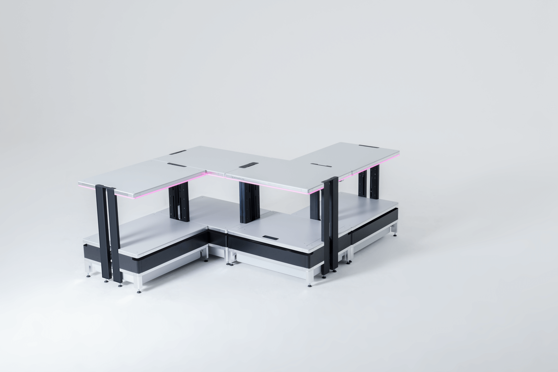 Modular white and black L-shaped workstation desk with two-tier shelves and pink LED lighting under the upper surfaces.