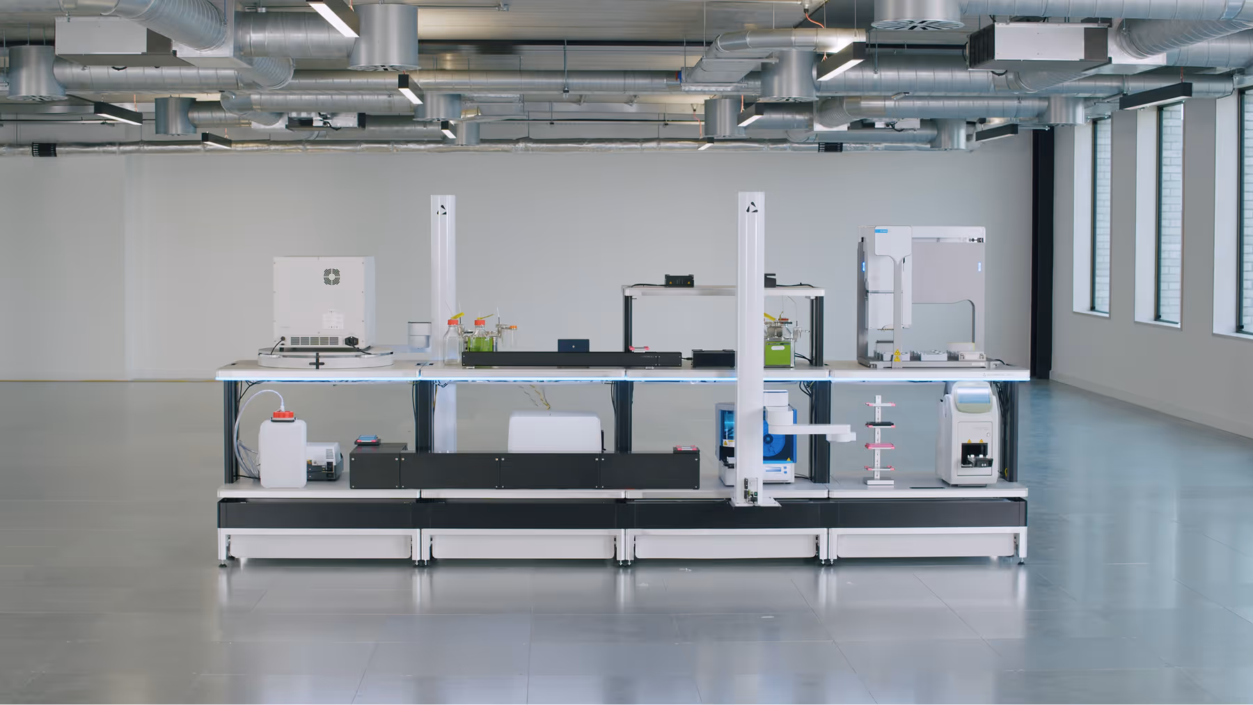 Modern automated laboratory bench with scientific instruments in a well-lit room.