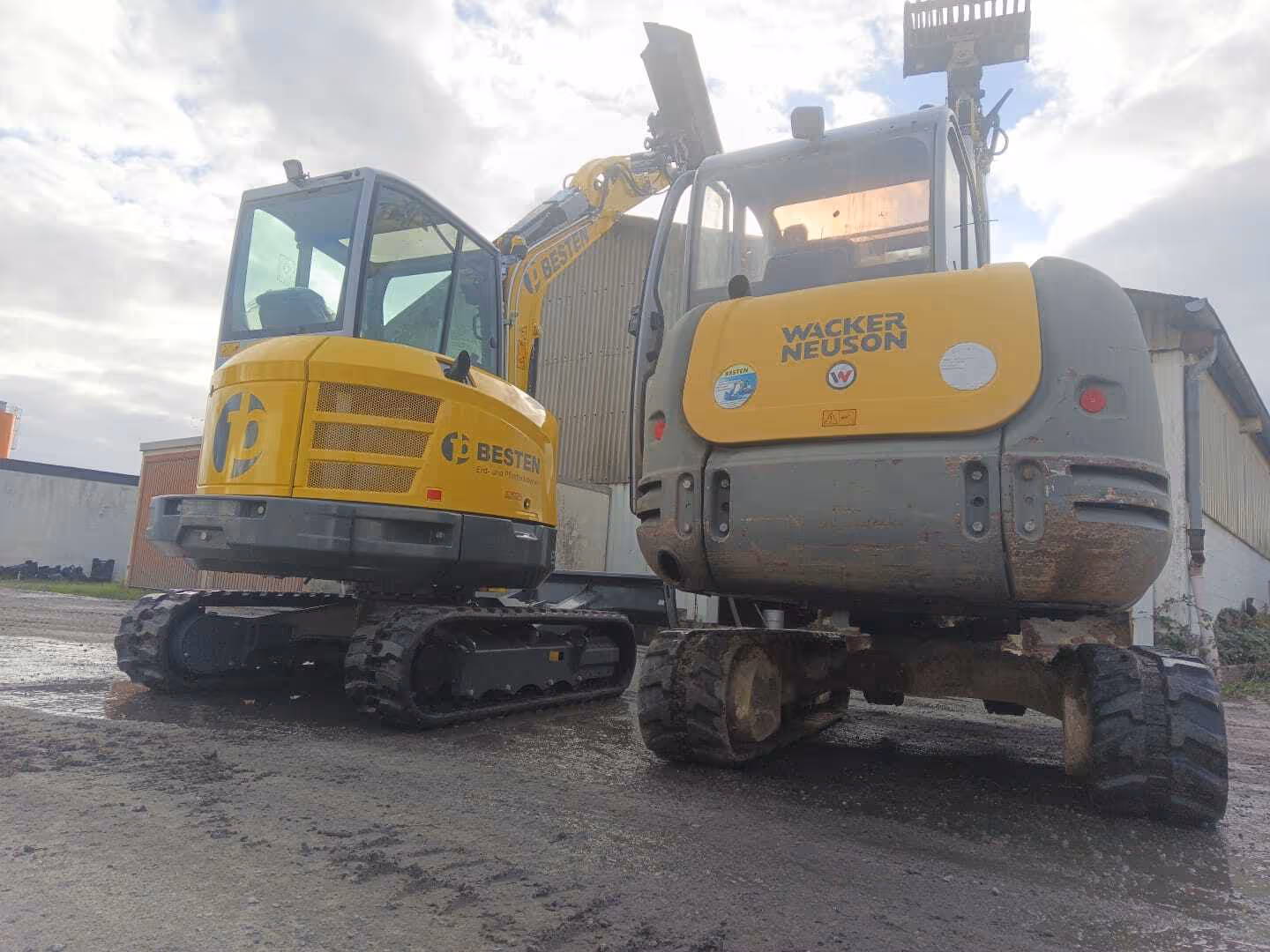 Zwei BESTEN-Bagger nebeneinander auf nasser Baustelle nach Regen