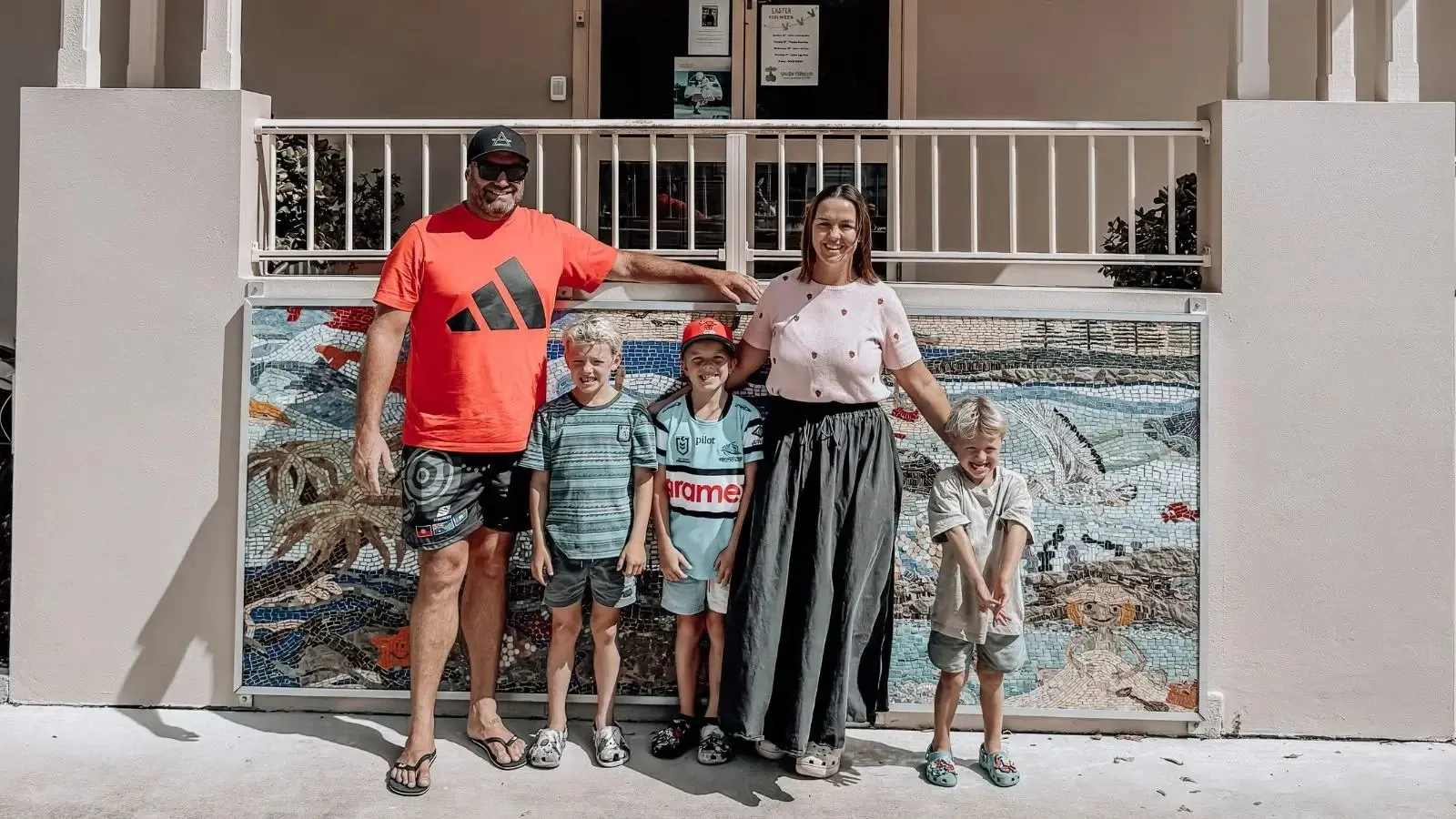 A family with two children standing in front of a mural.