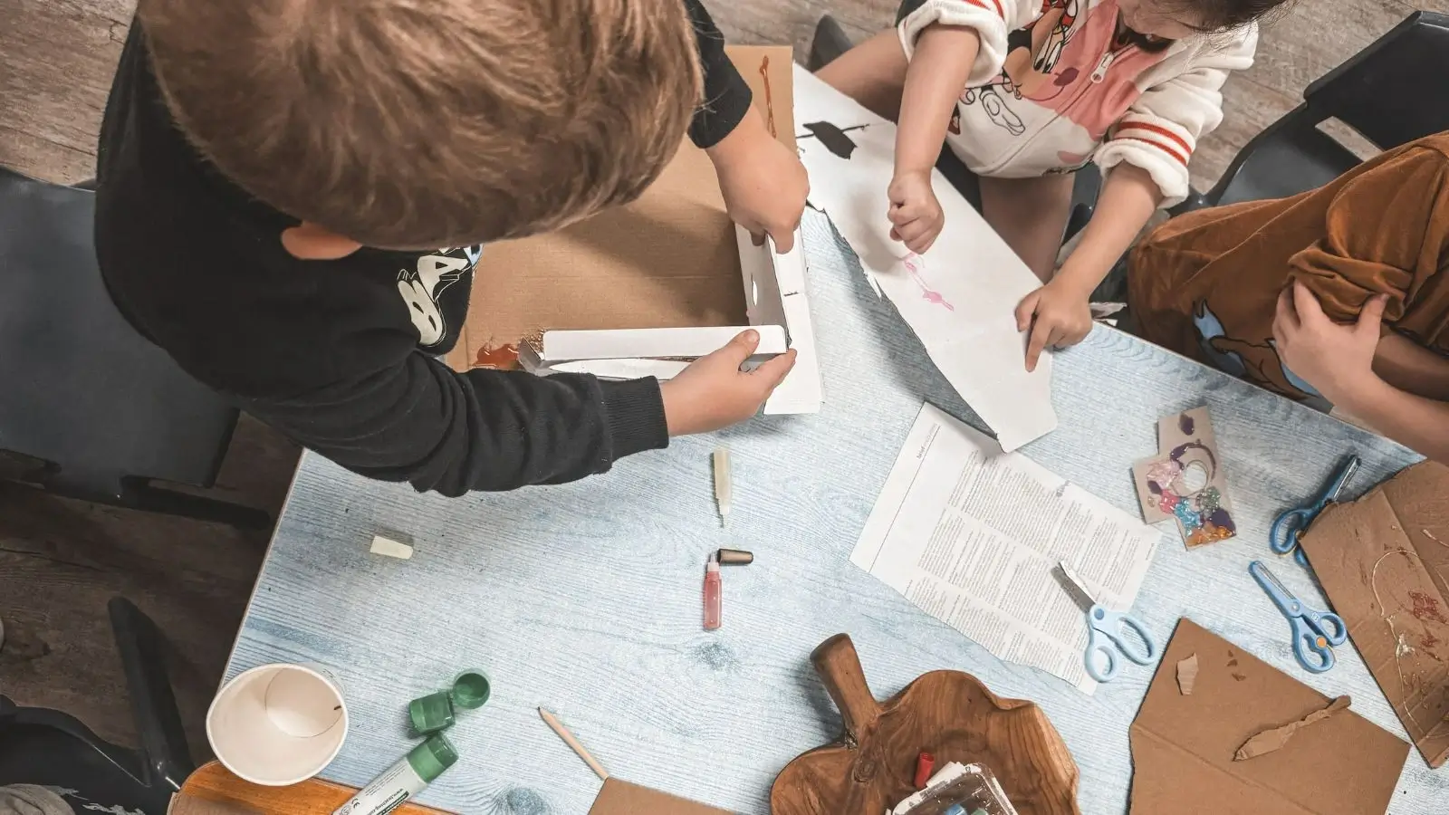 A group of kids sitting at a table working on crafts.