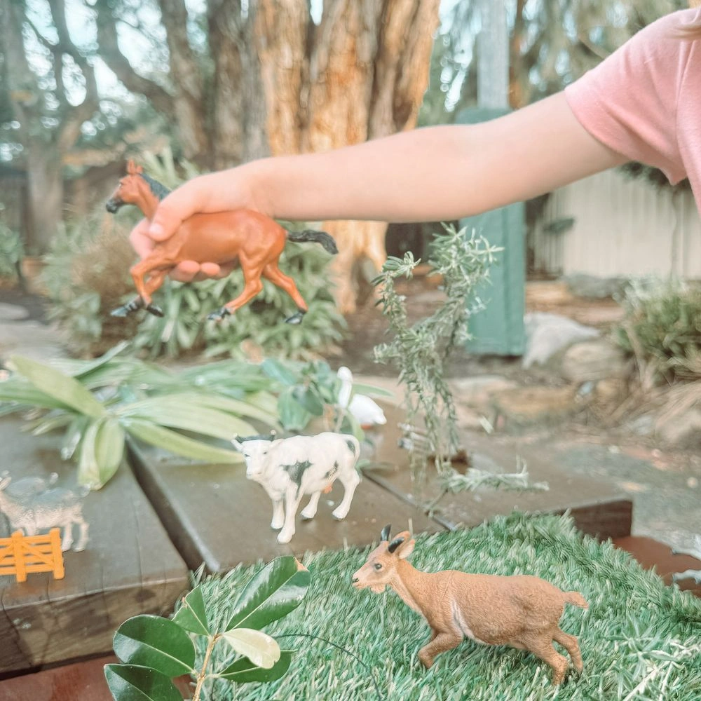 A little girl is playing with fake animals.