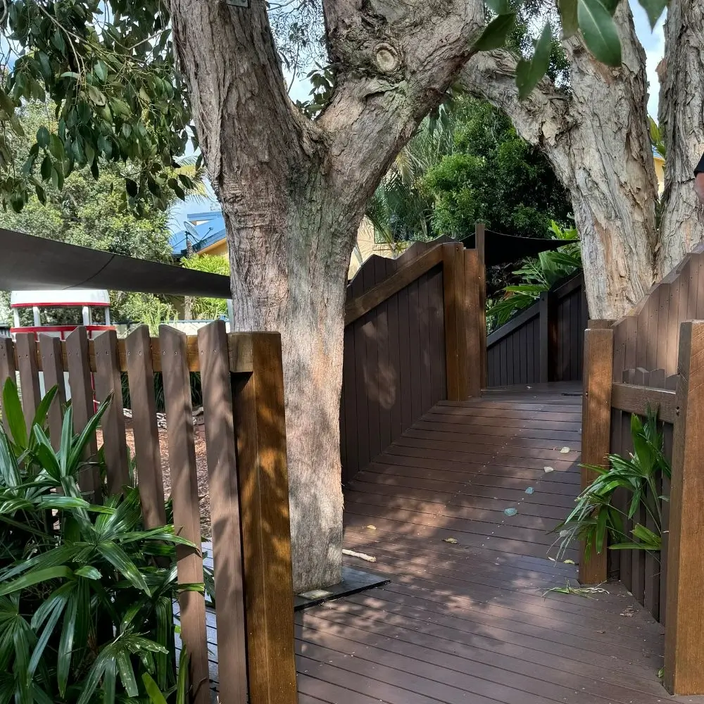 A wooden walkway between two large trees.