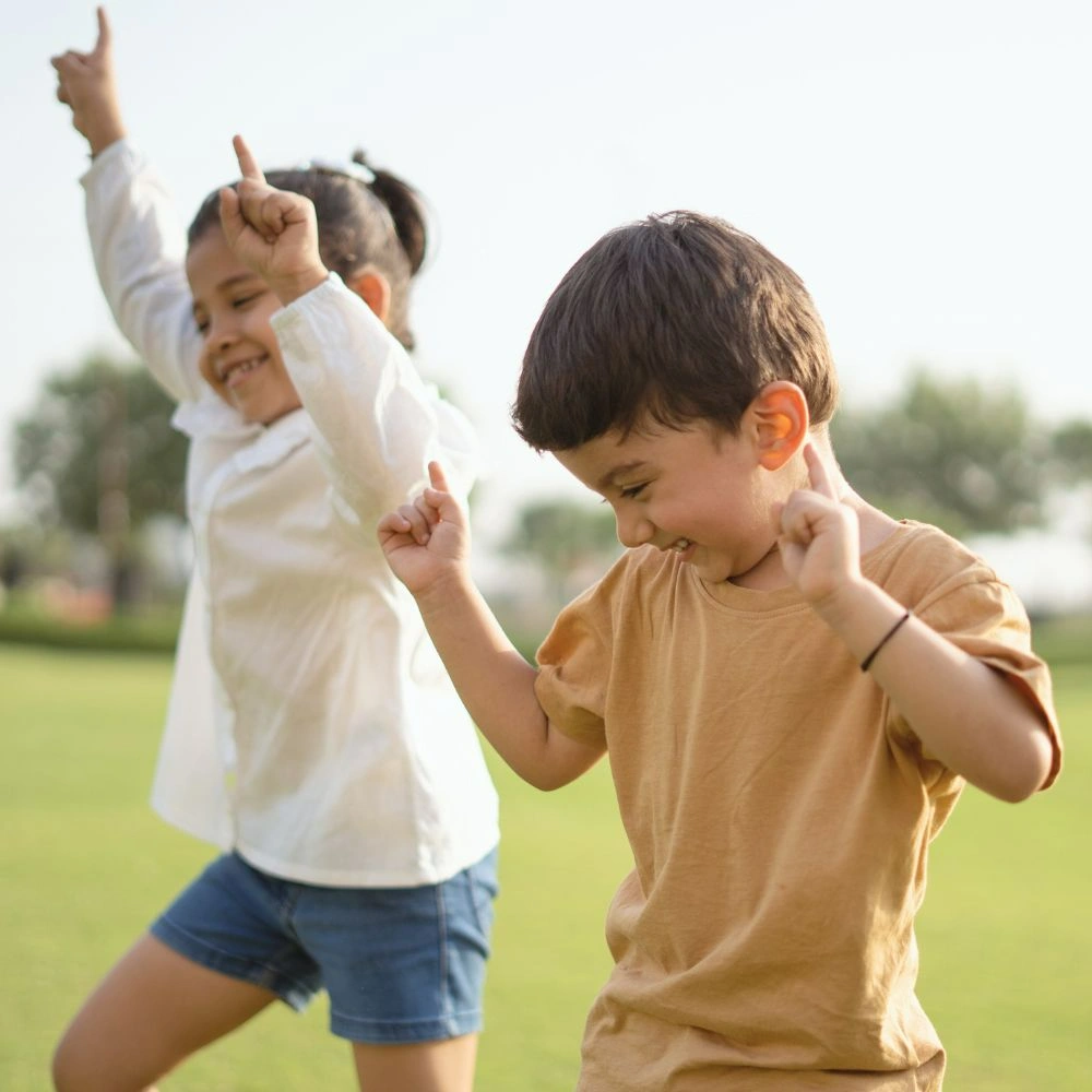 A couple of kids that are standing in the grass.