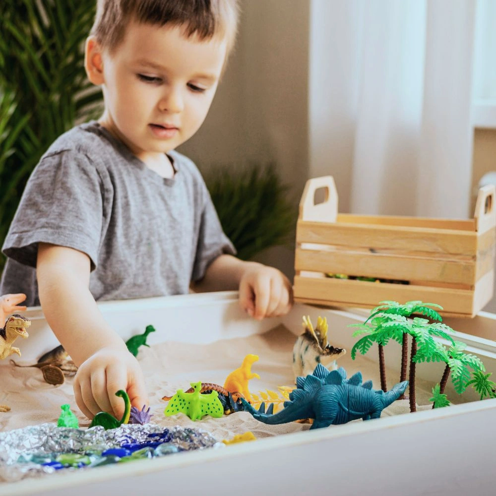 A young boy playing with toys in a play table.