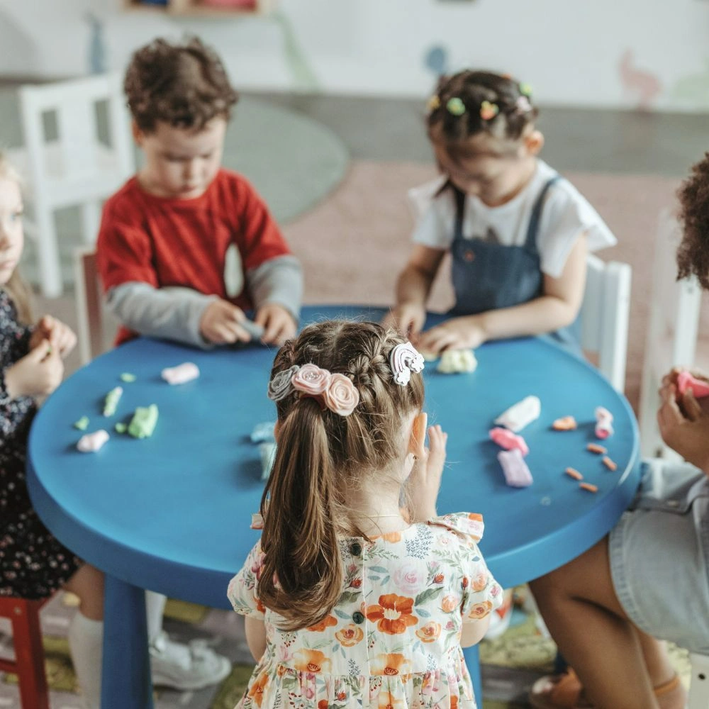 A group of children sitting around a blue table.