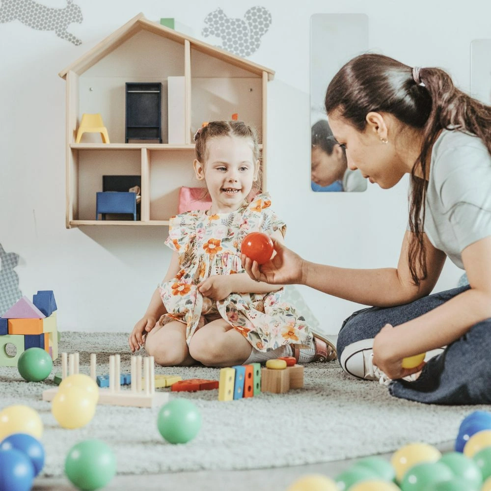 A woman playing with a child on the floor.