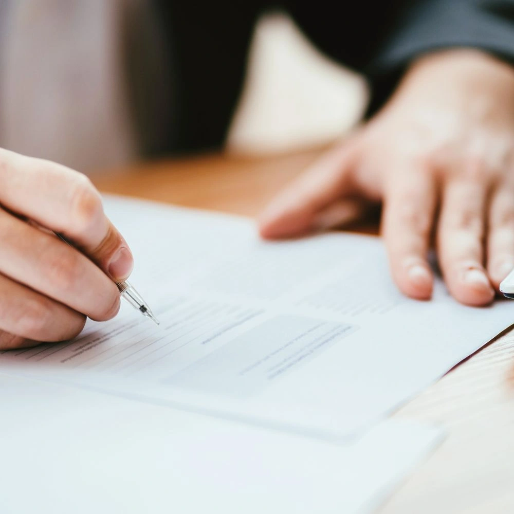 A person writing on a piece of paper with a pen.