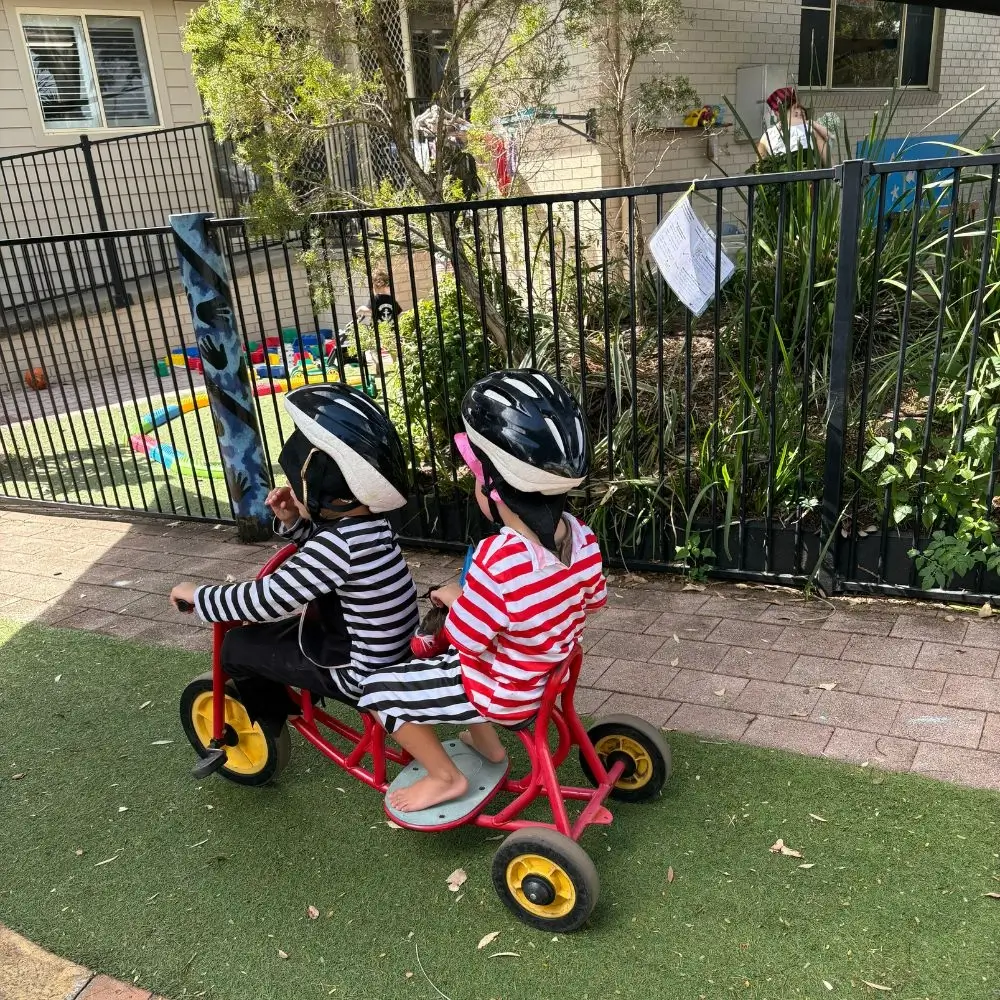 A couple of kids that are sitting on a bike.