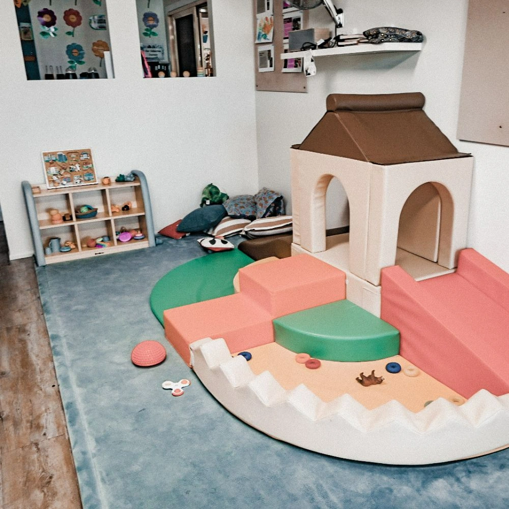 A child's play room with a play house and toys on the floor.