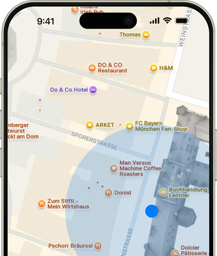 Close-up of a smartphone map showing locations in Munich including Do & Co Hotel, FC Bayern München Fan-Shop, and Man Versus Machine Coffee Roasters.