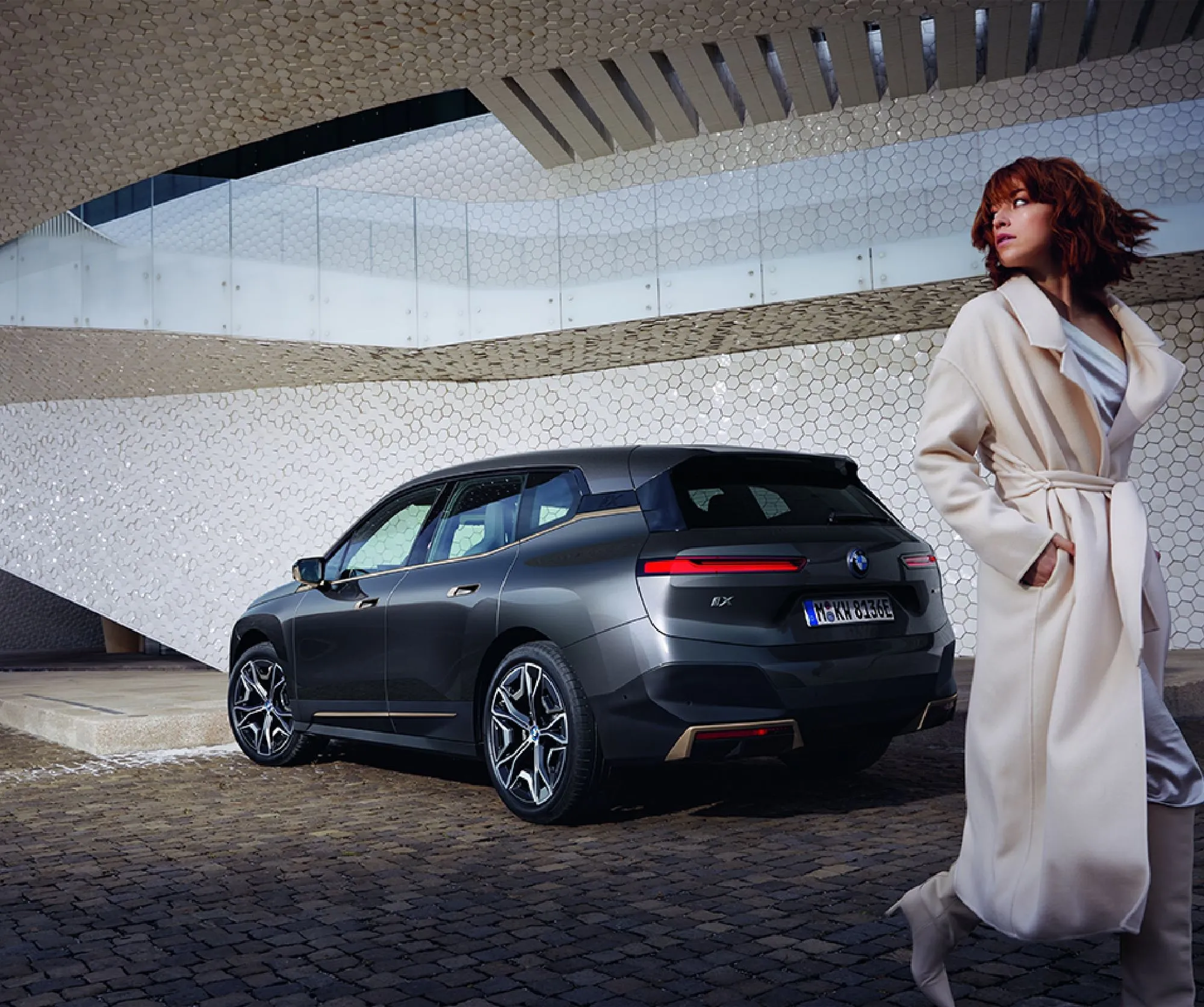 A person walking by a metallic grey BMW car