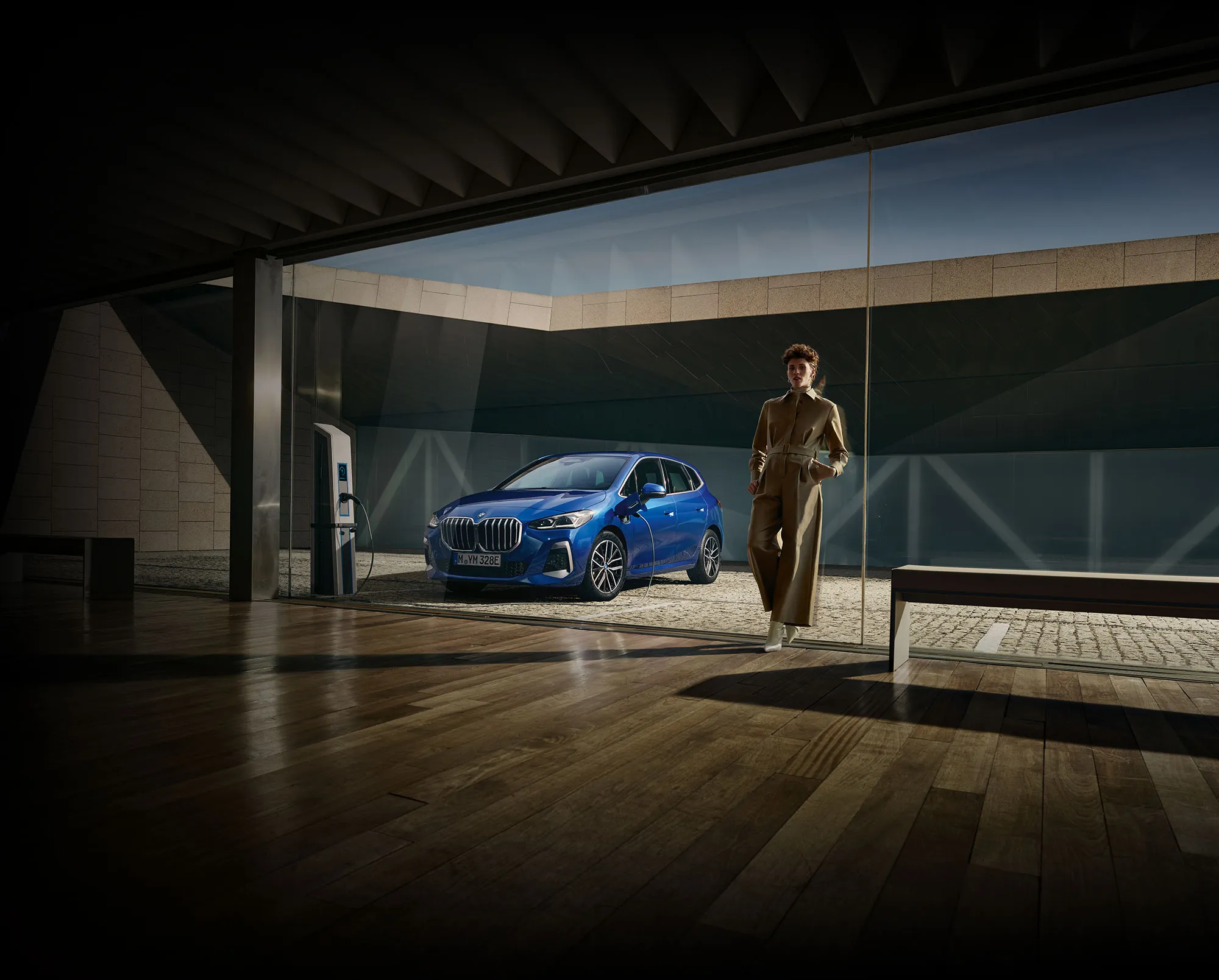 Website home page image, depicting a person posing next to a metallic blue BMW 530i car